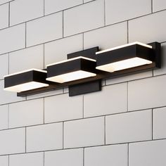 three lights on the side of a white brick wall