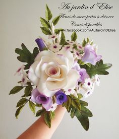 a hand holding a white and purple flower bouquet with words written on the back side