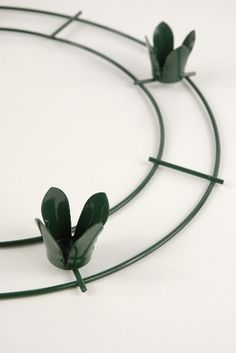 three green flowers are arranged in a circle on a white surface with thin metal bars