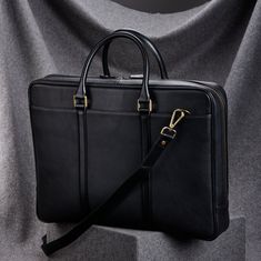 A handcrafted slim black leather briefcase for men, featuring top handles and three-sided zippers for easy access and secure storage of laptops and documents. Ideal for busy professionals, it seamlessly combines timeless elegance with practical functionality Exterior: Full grain leather in pebble embossed texture for durability. Top handles: Smooth textured full grain leather Interior: Dual compartments: one specially padded to cradle laptops/tablets, while the other offers ample space for organ