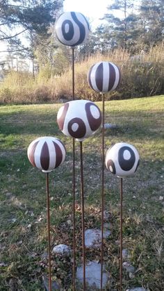 three metal sculptures with black and white designs on them in the grass near some trees