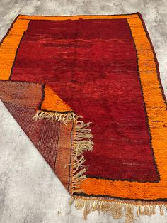 an orange and red area rug with fringes on the bottom, next to it