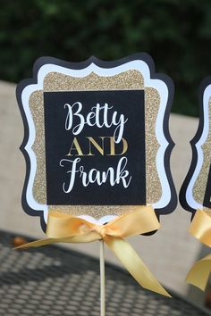 two black and gold wedding signs on sticks