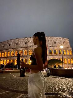 a woman standing in front of the colossion at night