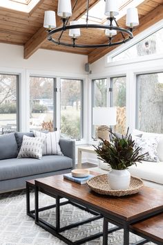 a living room filled with furniture and windows covered in wood planks on the ceiling