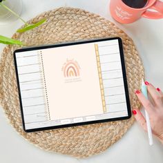 a woman's hand holding a pen and looking at a tablet with a notepad on it