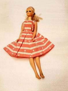 a doll is laying on the floor wearing a red and white striped dress with her hair in pigtails