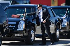 a man in a suit and tie standing next to some cars