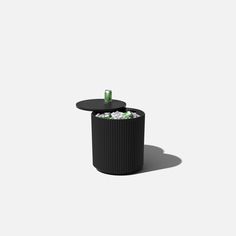 a black trash can sitting on top of a white floor next to a round table