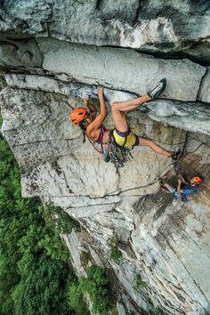 a woman climbing up the side of a cliff