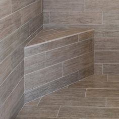 a walk in shower sitting next to a tiled wall and floor covered in brown tile