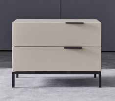 a white and black dresser sitting on top of a carpeted floor next to a wall