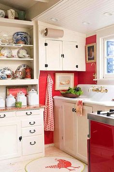 a red stove top oven sitting inside of a kitchen next to a sink and cabinets