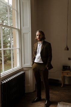 a man standing in front of a window next to a radiator