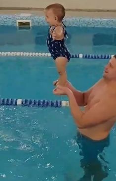 a man holding a baby in the pool