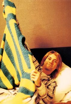 a man laying in bed with a stuffed animal on top of his head and holding it up