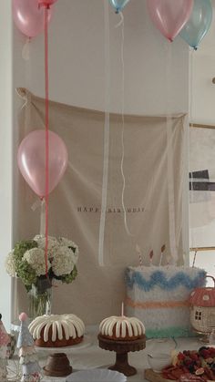 some balloons are hanging from the ceiling above cakes and desserts on a table with flowers in vases