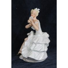 a ceramic figurine of a woman in a white dress sitting on a black background