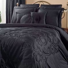 the comforter is black and has an intricate design on it, along with matching pillows