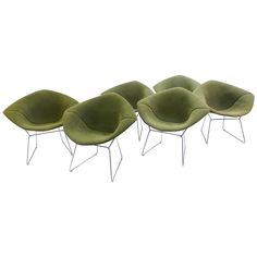 four green chairs with metal legs and one has a white back ground, while the other is