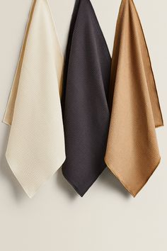 three different colored ties hanging on a wall next to each other, one black and one gold