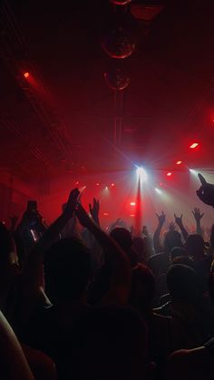 a group of people in a dark room with their hands up and lights on the ceiling