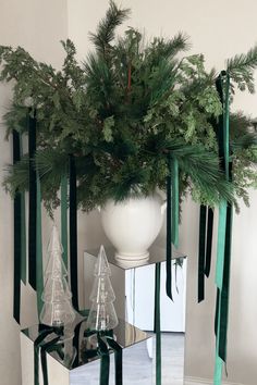 a vase with pine branches in it sitting on a table next to other christmas decorations