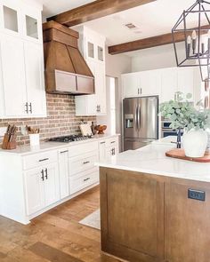 a kitchen with white cabinets and wood flooring is pictured in this image, the island has a potted plant on it