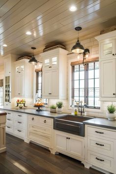 a large kitchen with white cabinets and black counter tops is pictured in this image, there are two windows above the sink