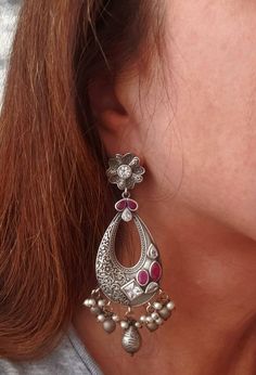 Stunning German silver Indian Chandbali earrings, embellished with sparkly cut CZ stones. Eye catching asymmetric design with a scrolling floral pattern on one half of the earring, and the CZ stones on the other half! Beautiful dangly pearls and silver color stamped balls move when you move, in a very alluring way! Pretty ear stud in shape of flower. Grey finish, polished to a lovely soft lustre. Lots of intricate detail! Excellent quality and craftsmanship! Length 3 3/4 in Width 2 in Weight 14 Silver Chandbali Fusion Jewelry, Silver Pearl Earrings With Stone Work For Gift, Silver Pearl Earrings With Stone Work For Celebration, Wedding Silver Chandbalis With Intricate Design, Silver Fusion Bridal Earrings With Intricate Design, Silver Temple Jewelry Chandelier Earrings With Intricate Design, Silver Fusion Chandelier Earrings, Silver Chandbali Hoop Earrings For Celebration, Sterling Silver Chandbali Danglers In Temple Jewelry Style