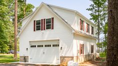 a white two story house with red shutters