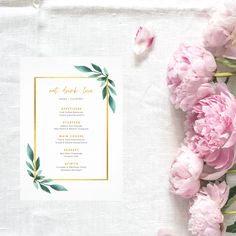 pink peonies and greenery on a white table cloth next to a menu card