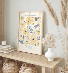 a shelf with baskets and vases on it next to a framed flower art print