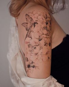 a woman's shoulder with flowers and a butterfly tattoo on her left upper arm