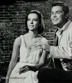 an old black and white photo of a man sitting next to a woman in front of a brick wall