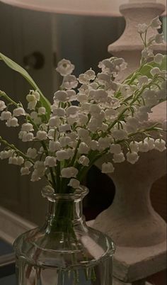 a vase filled with white flowers sitting on top of a table next to a lamp