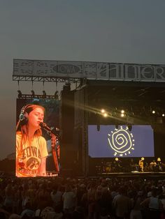 a woman standing on top of a stage in front of a large screen with headphones