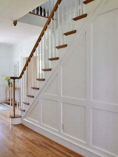 a white staircase with wooden handrails and wood flooring in a home's entryway