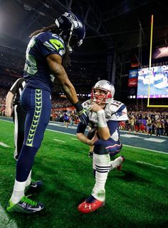 two football players on the field, one is holding the other's hand and saying get up pretty boy you look like a fool