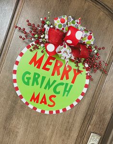 a merry grinmas door hanger on a wooden door with red and green decorations