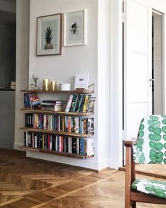 a living room filled with furniture and a book shelf next to a doorway that has pictures on the wall