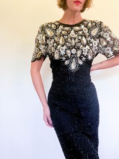 vintage Lawrence Kazar fully embellished 100% silk cocktail dress / black gold white / floral paisley look / keyhole back / flutter sleeves ⚡️ labeled size large (modeled on size small, 5'5") ⚡️lying flat: shoulders 16" pit to pit 18" waist 14.5" hips 18.5" length 38" sleeve length 9" ⚡️small section on seat that needs repair of barrel beads, very small part of right hip beads. overall great condition for a dress of this kind. --------------------------------------------------------------------- Vintage Embellished Silk Dress, Vintage Silk Dress With Sequins, Vintage Silk Dress With Beading, Vintage Beaded Silk Dress, Vintage Beaded Dresses For Night Out, Vintage Silk Beaded Dress, Hip Beads, Silk Cocktail Dress, Black Cocktail Dress