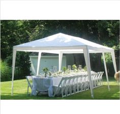 a white tent with tables and chairs set up for an outdoor dinner in the grass