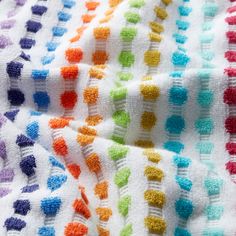 a multicolored crocheted blanket laying on top of a bed