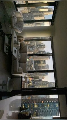 the interior of a room with high rise buildings in the background, looking down at the floor to ceiling windows