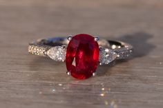 an oval shaped ruby and diamond ring on a wooden surface