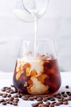 coffee being poured into a glass filled with liquid