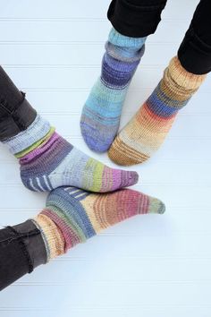 two people standing next to each other with their feet up wearing socks that have multicolored stripes on them