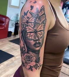 a woman's arm with a butterfly and rose tattoo on her left shoulder,