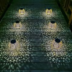 several lights that are on top of a wooden floor in the night time with shadows